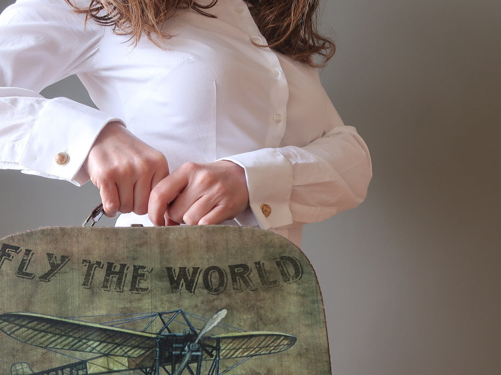 woman holding up a suitcase wearing cufflinks