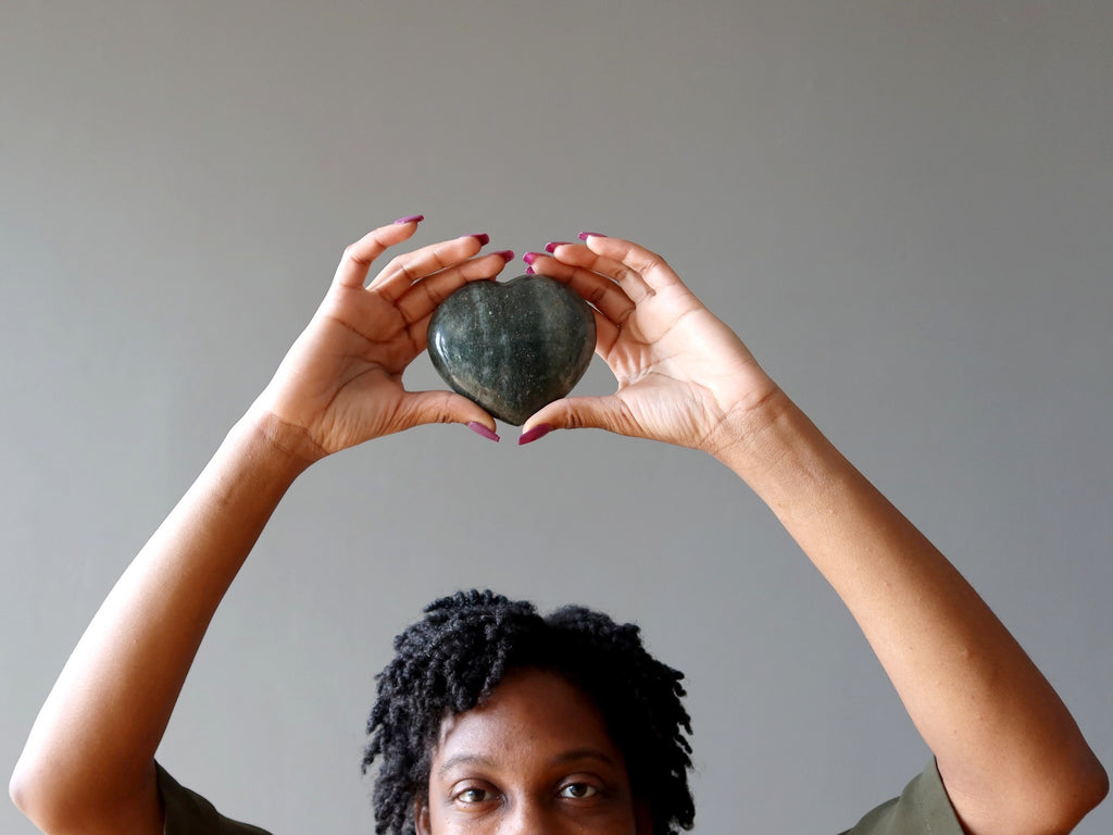 woman holding green aventurine heart above head