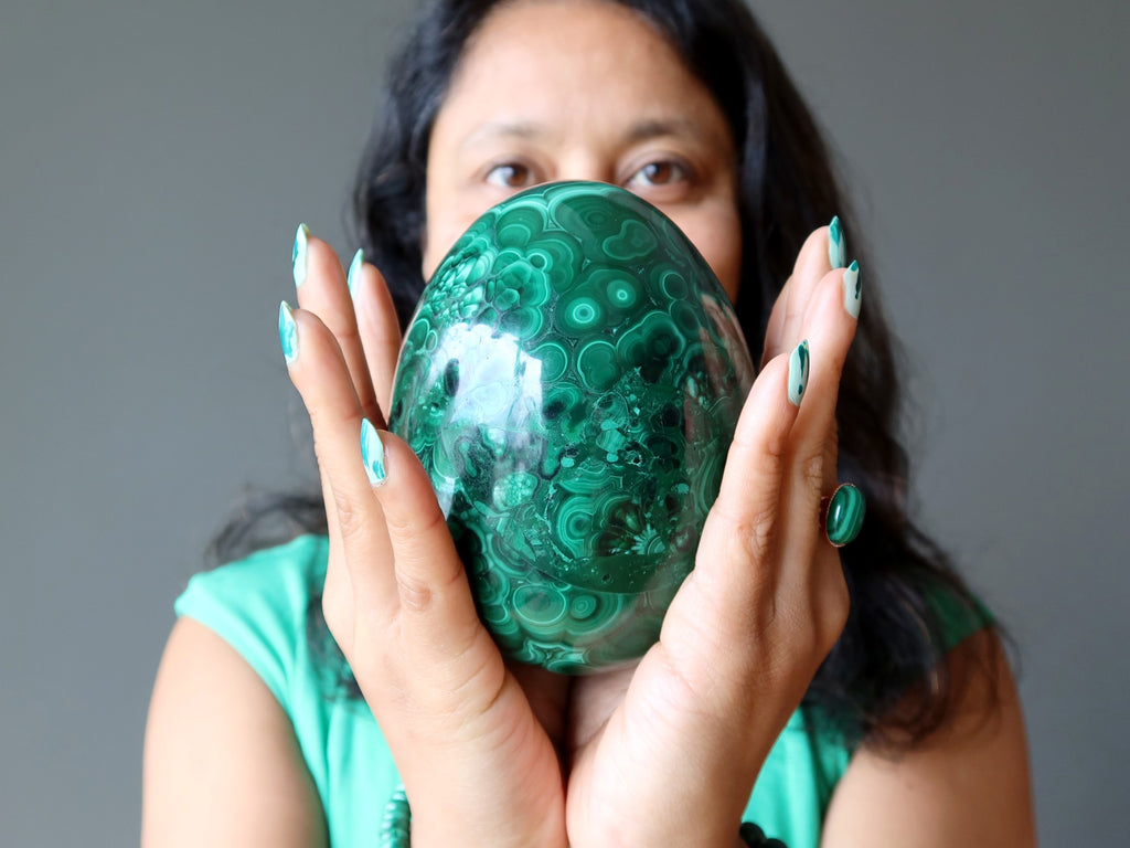 female holding large malachite egg in both hands