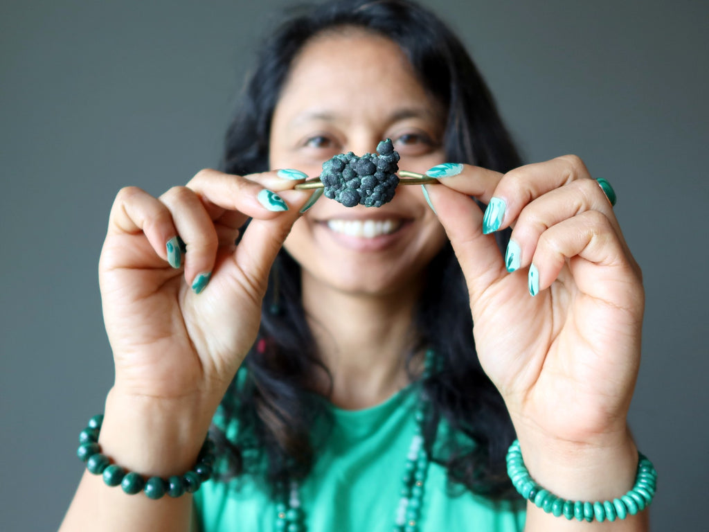 sheila of satin crystals holding up a raw malachite bracelet