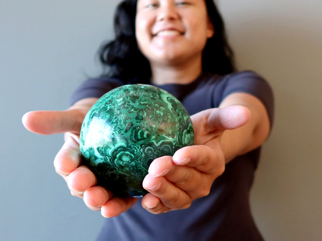 female holding malachite lucky clover ball