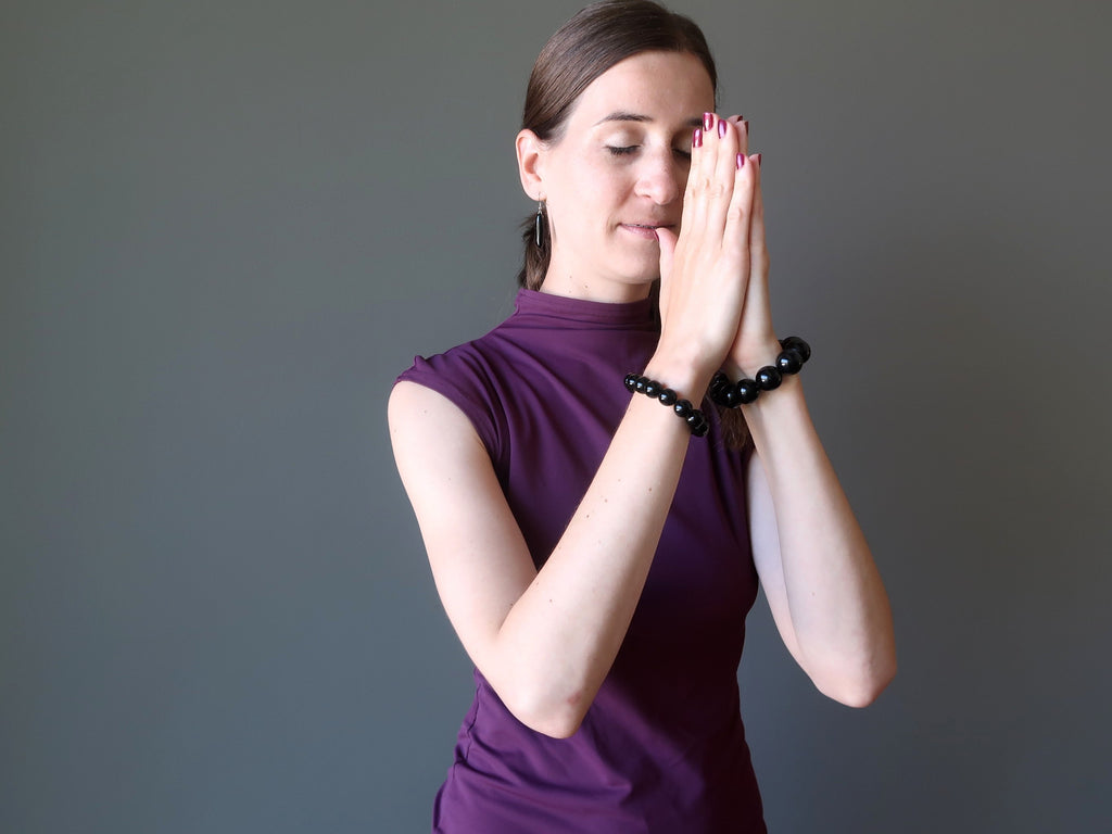 lucia of satin crystals wearing obsidian stretch bracelets in meditation pose