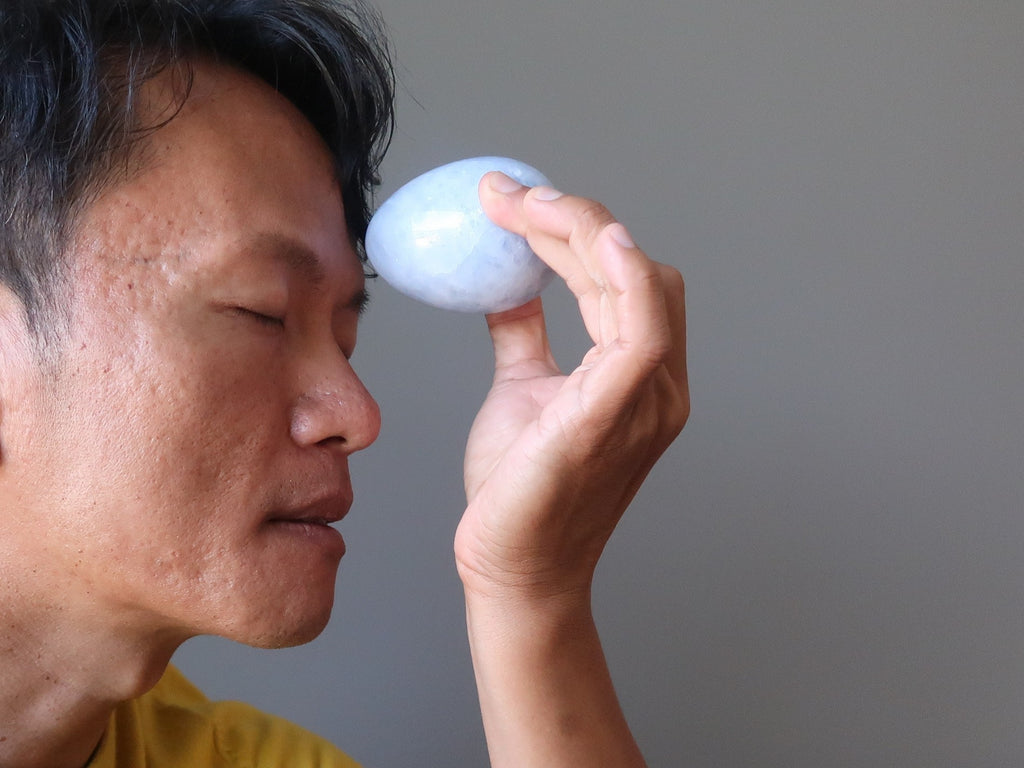 tim of satin crystals meditating with a blue calcite stone egg at his third eye chakra