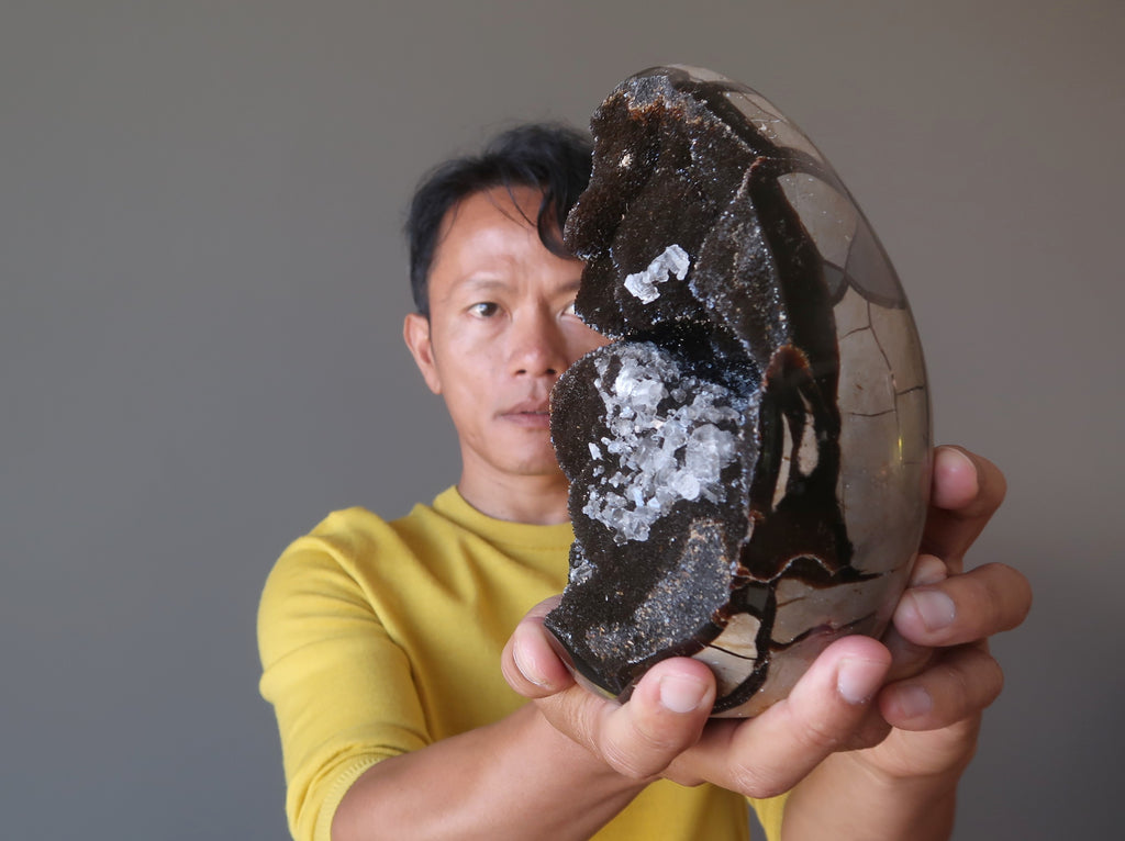 tim of satin crystals focusing on a giant septarian druzy quartz stone egg for meditation