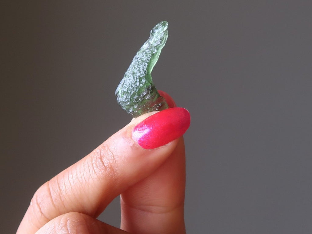hand holding up a gemmy green moldavite tektite meoteorite