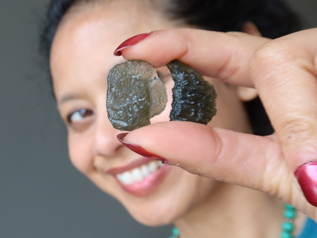 sheila of satin crystals holding up two moldavite gemstones