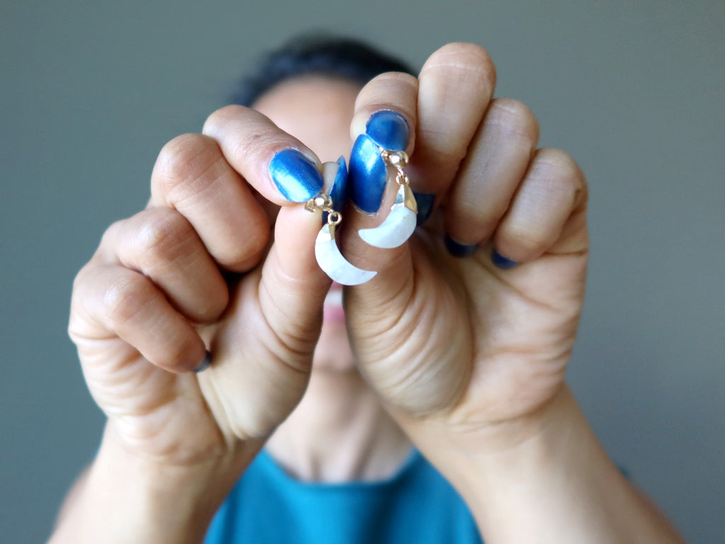 woman holding moonstone moon earrings