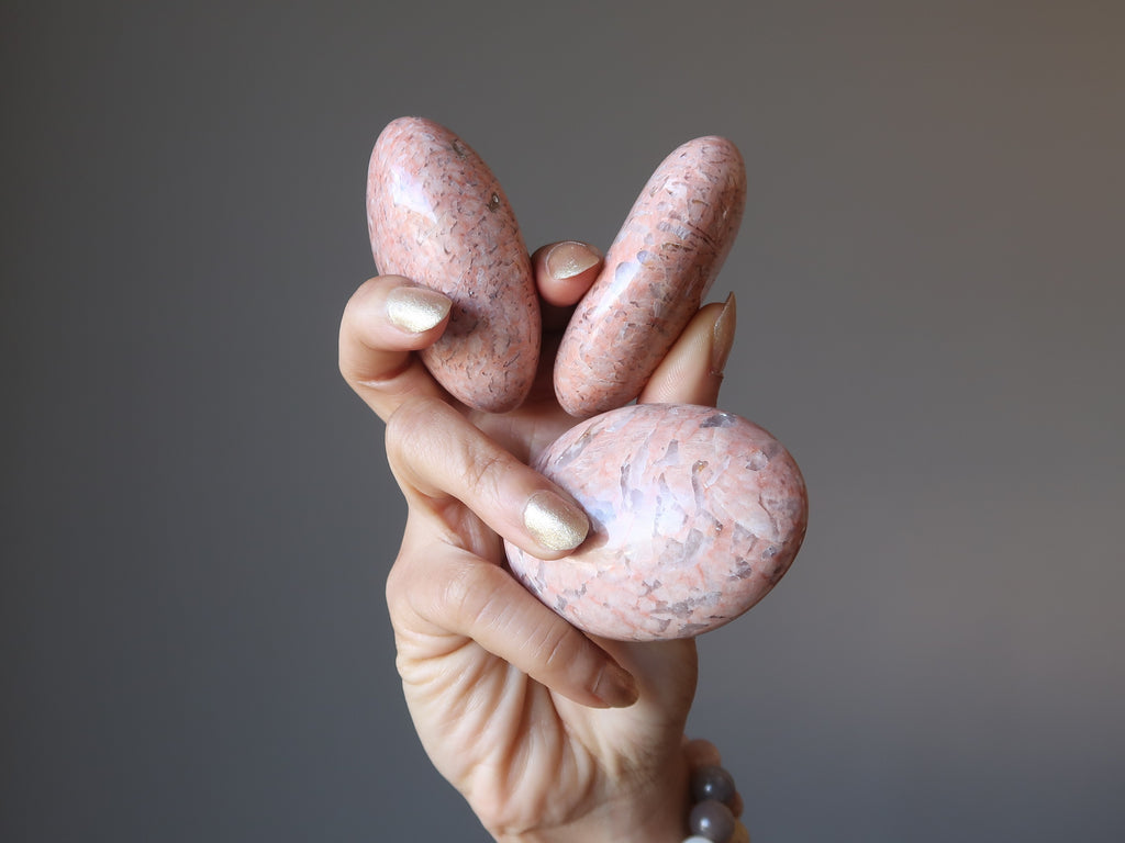 hand holding three peach moonstone slabs