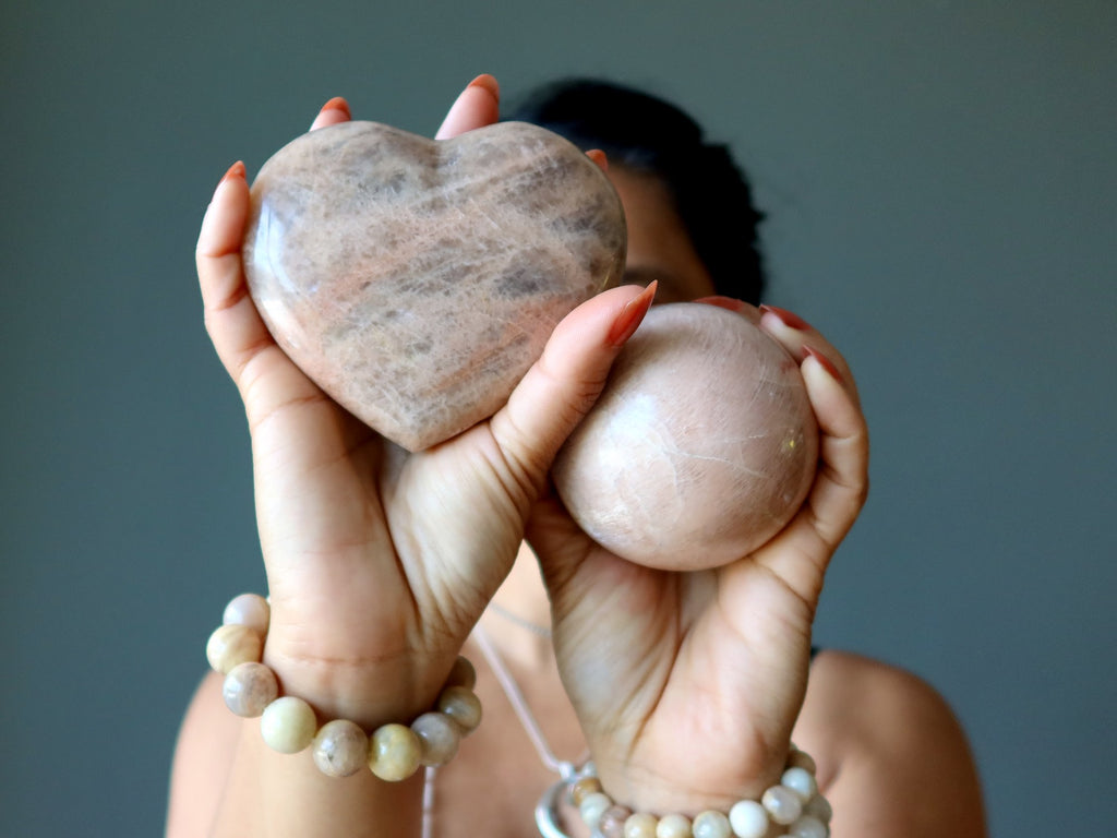 woman holding peach moonstone heart and sphere