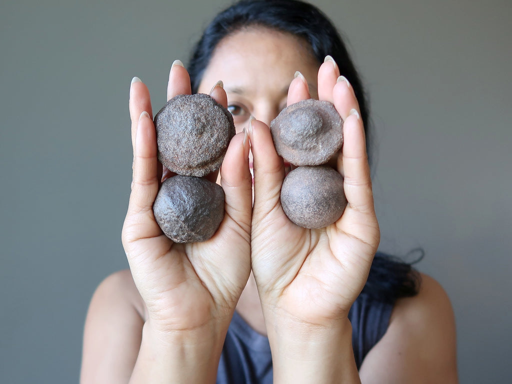 sheila of satin crystals holding 4 moqui marble stones in the palm of her hands