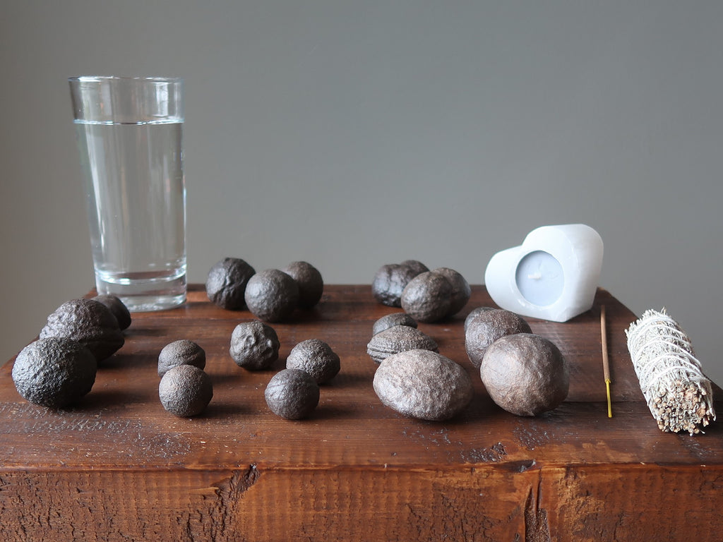 table full of moqui marble stones, candle, incense, sage and water