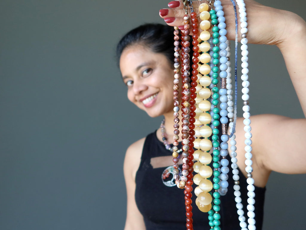 woman holding chakra necklaces