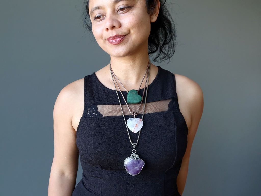 woman wearing three gemstone heart necklaces