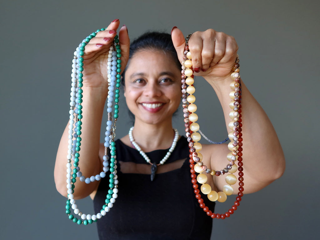 sheila of satin crystals holding two bunches of beaded necklaces