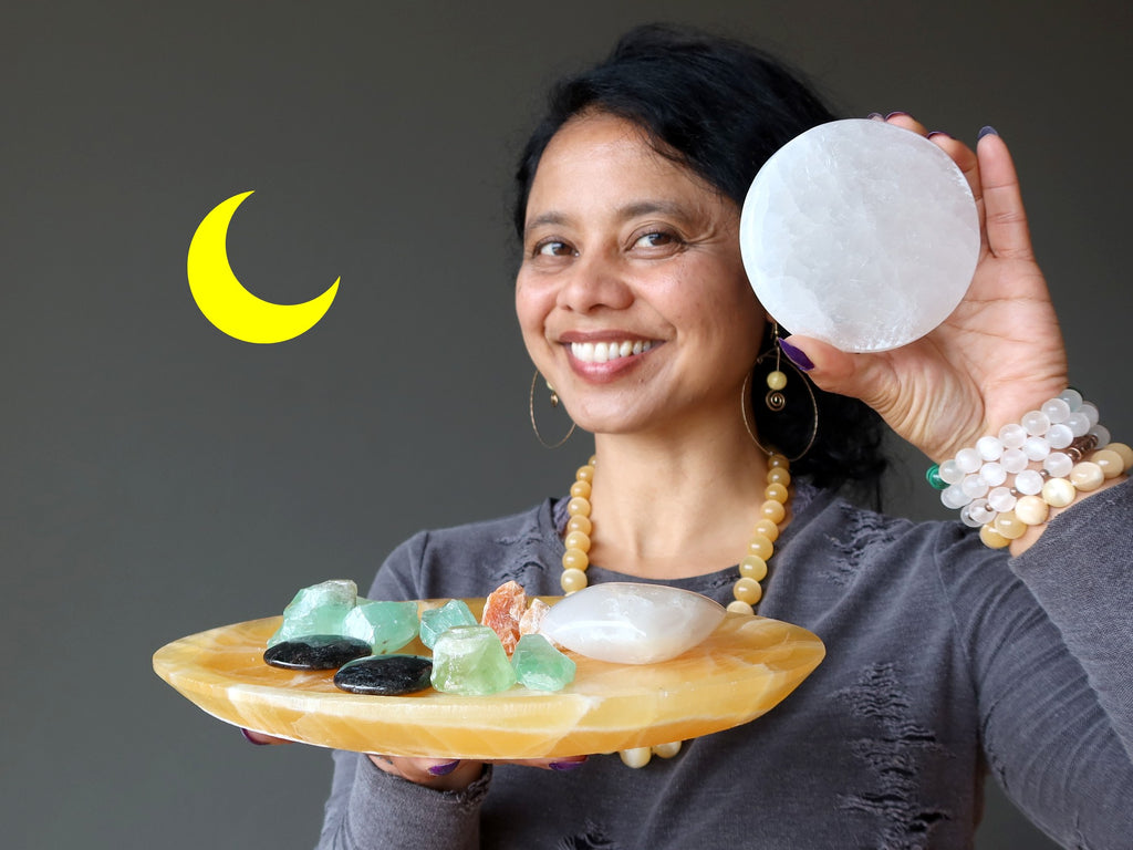 sheila of satin crystals holding selenite circle, wearing selenite bracelets, holding calcite platter