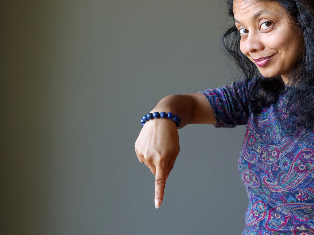 sheila of satin crystals wearing a lapis bracelet and pointing downwards
