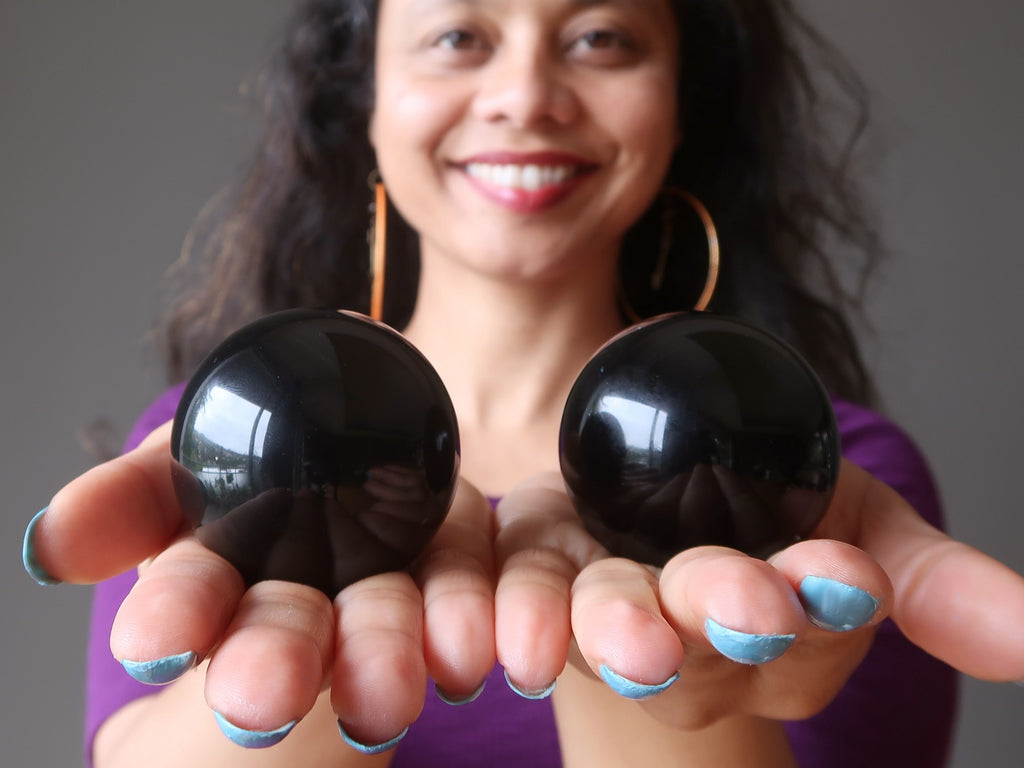 sheila of satin crystals holding out two rainbow obsidian spheres