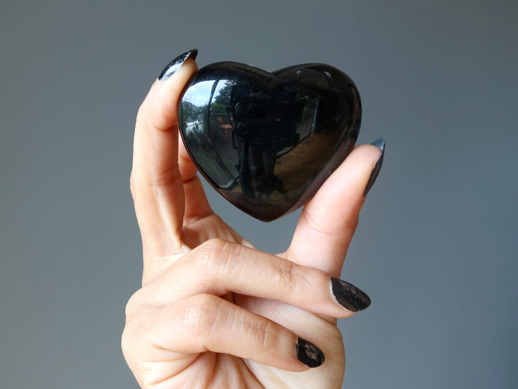 hand holding a rainbow obsidian heart
