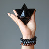 hand wearing obsidian bracelets and holding a black obsidian merkaba