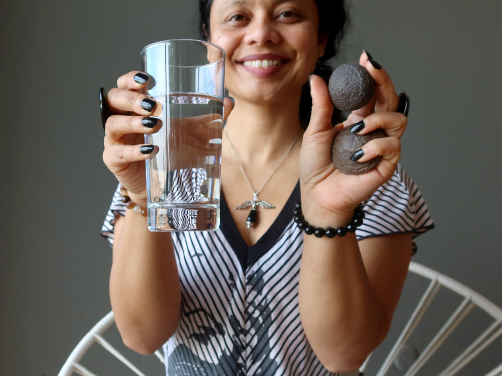 sheila of satin crystals holding a glass of water and pair of moqui marbles