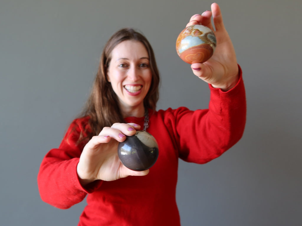 woman holding two picture jasper spheres