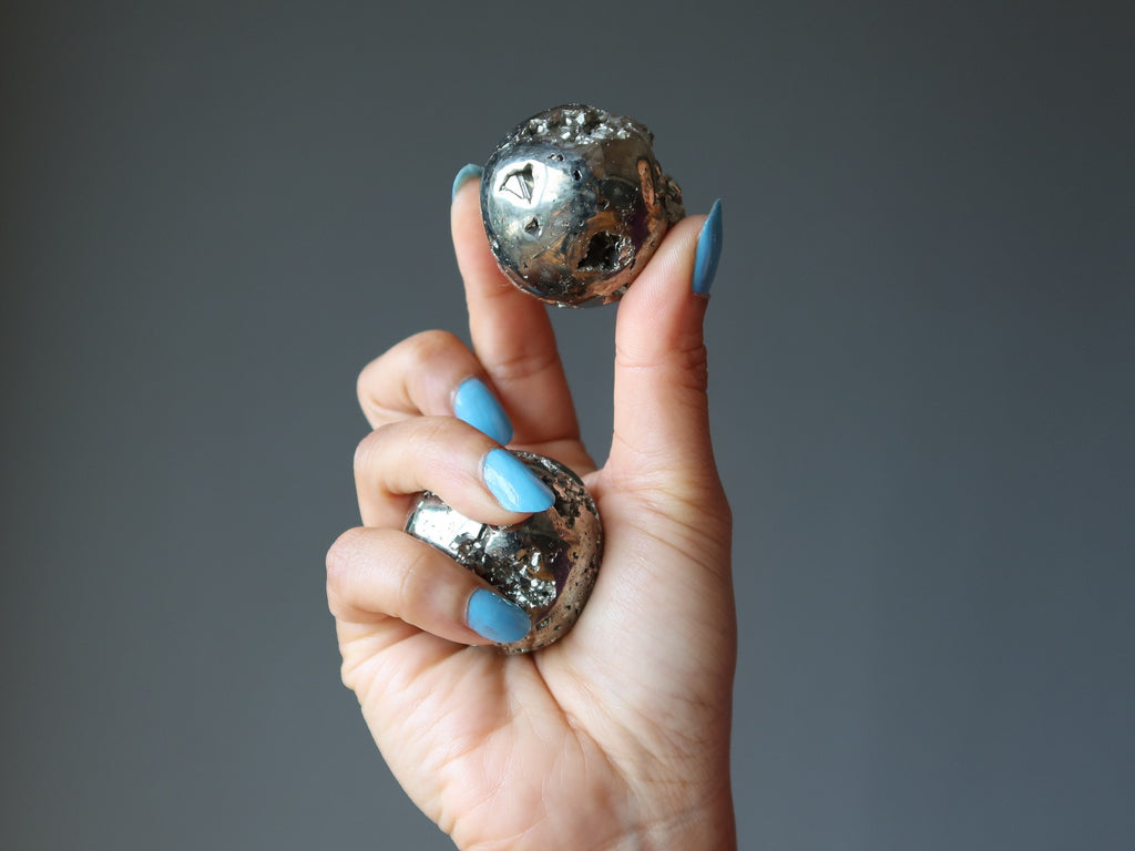hand holding pyrite spheres