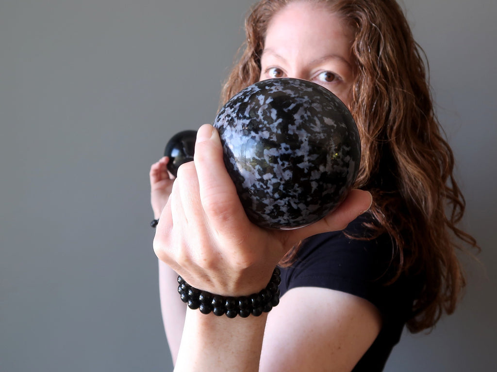 jamie of satin crystals holding up a gabbro crystal healing ball sphere