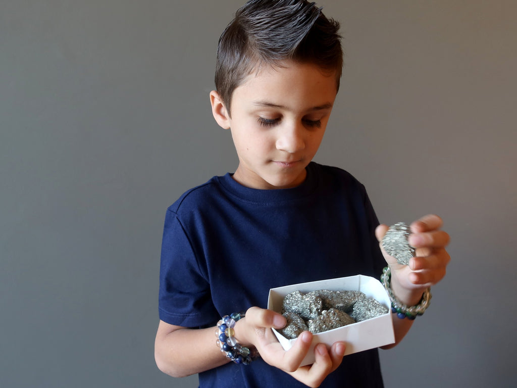 male kid choosing from a box of pyrite clusters