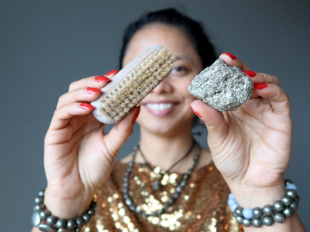 sheila of satin crystals holding a scrub brush and a pyrite cluster