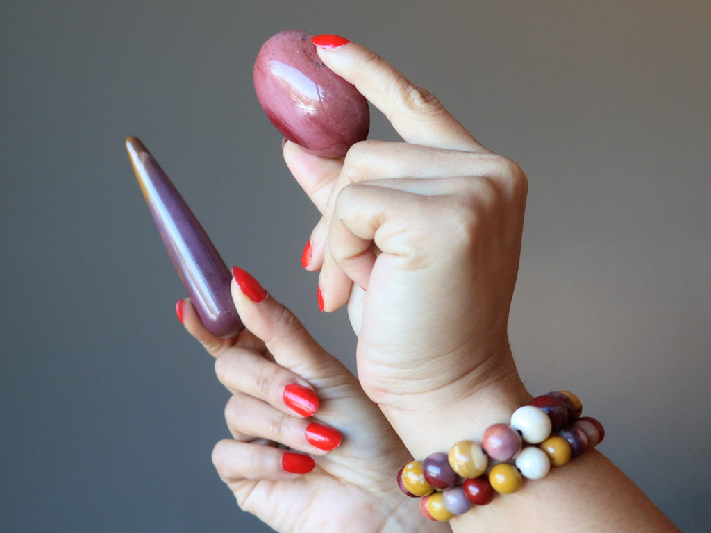 hands wearing mookaite jasper bracelets, holding a mookaite jasper oval and massage wand