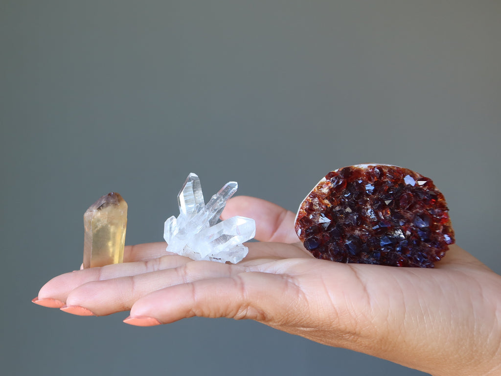 natural citrine, quartz cluster, and heated citrine geode in palm of hand
