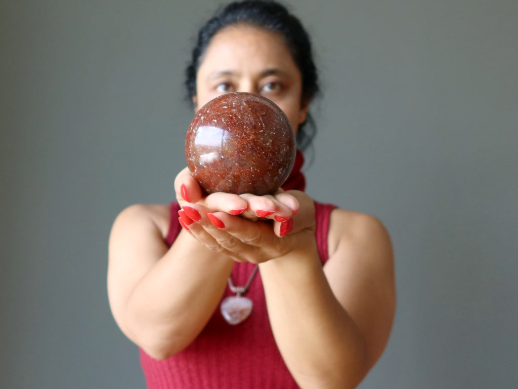 sheila of satin crystals holding red hematite quartz sphere