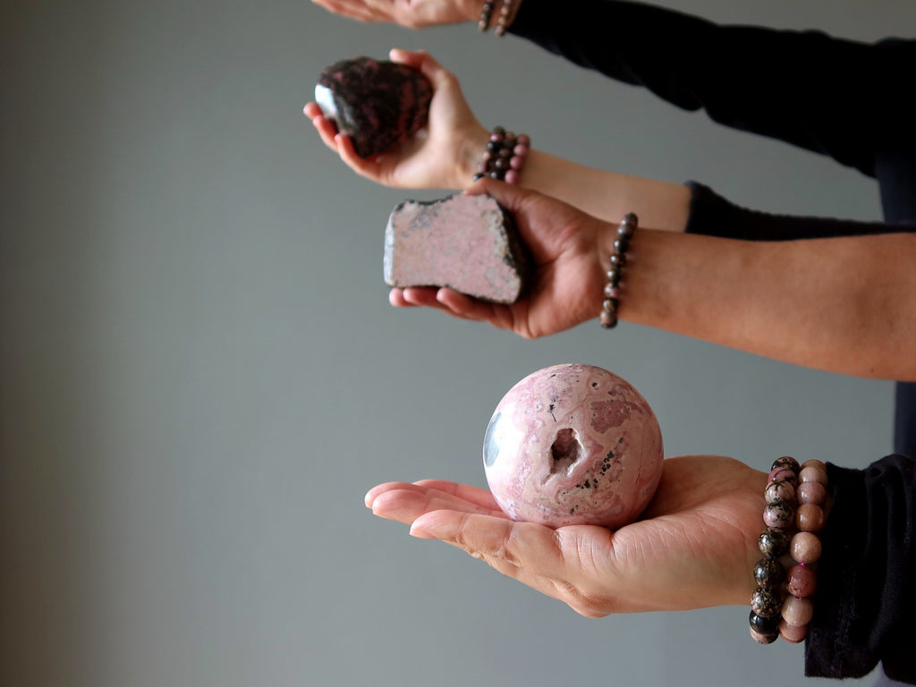 hands holding rhodonite