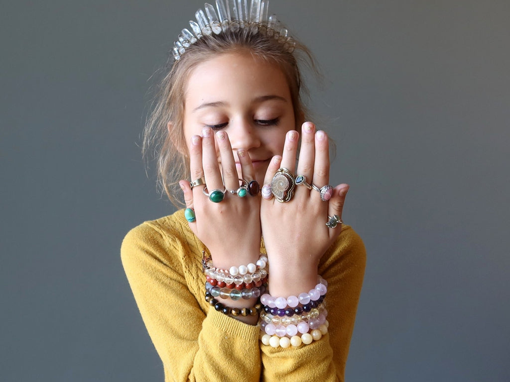 girl wearing a lot of bracelets, jewelry and quartz crown