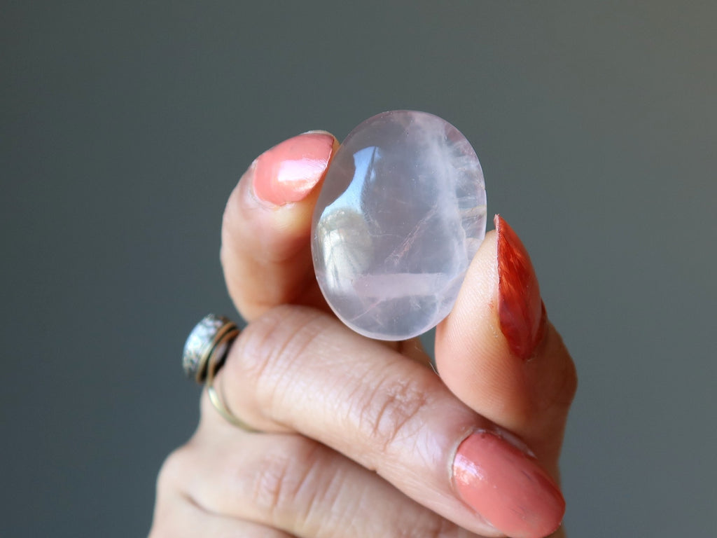 hand holding up an oval rose quartz cabochon