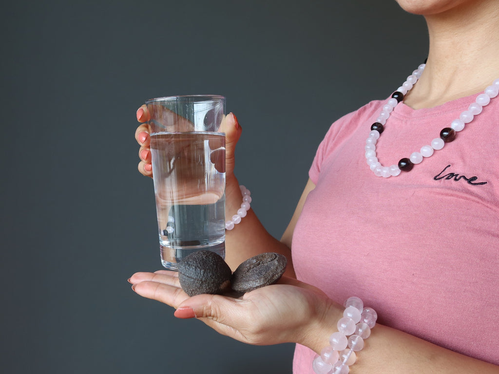 female holding moqui marbles and glass of water