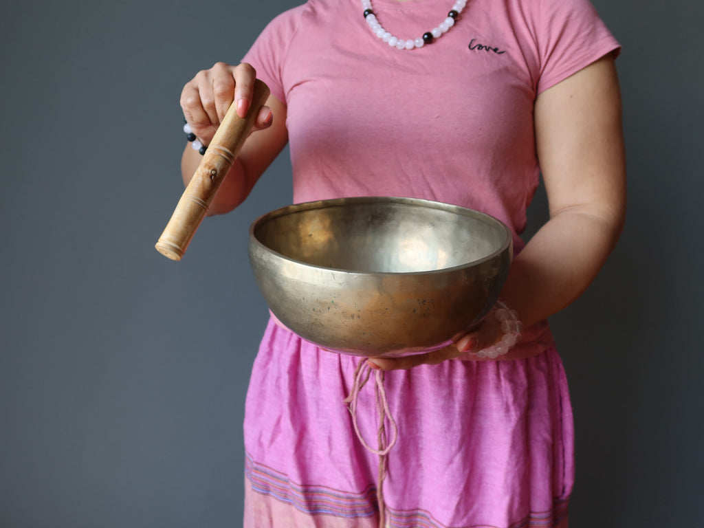 female dressed in pink playing tibetan singing bowl