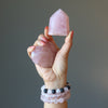 hand wearing rose quartz bracelets and holding rose quartz crystals