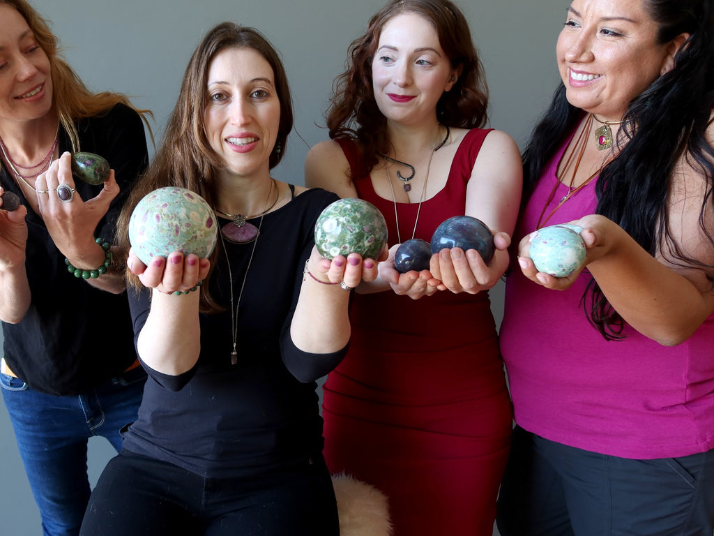 four women holding ruby stones