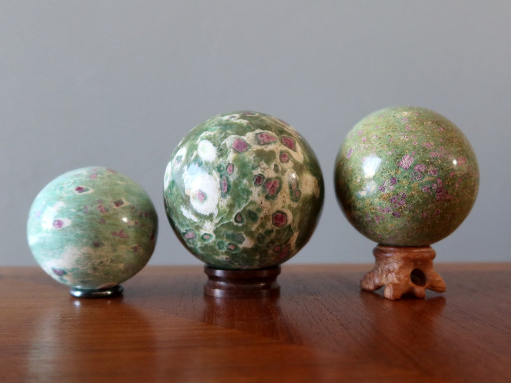 three ruby fuchsite spheres on stands