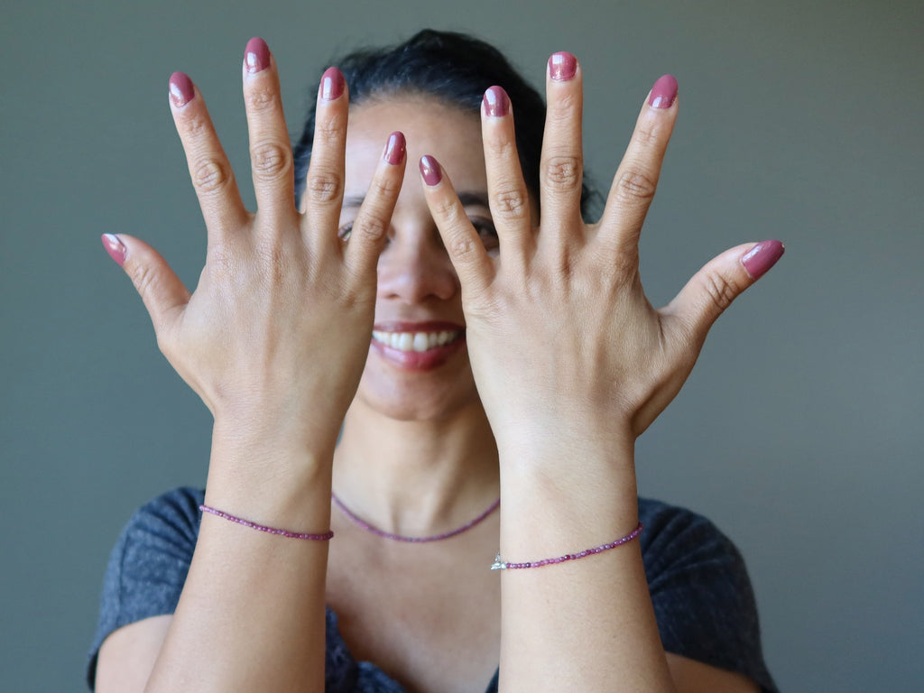 woman wearing faceted ruby bracelets on each wrist
