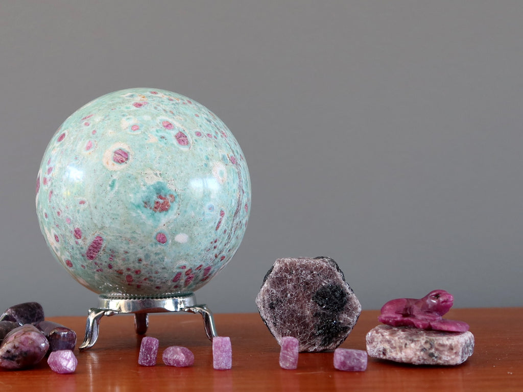 ruby fuchsite sphere and ruby raw stones on shelf