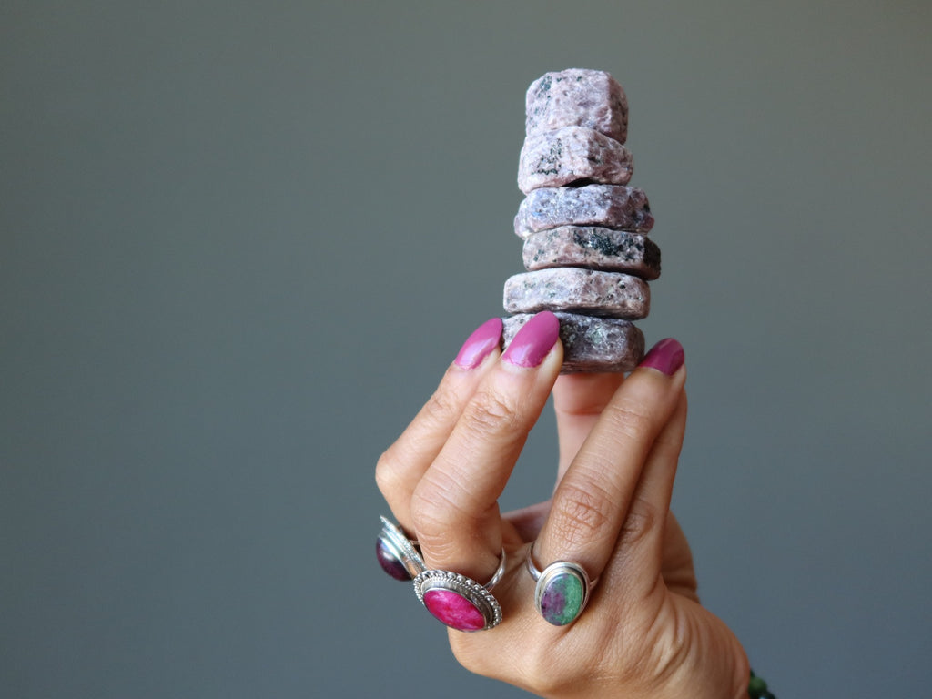 hand wearing ruby rings holding stack of ruby hexagons