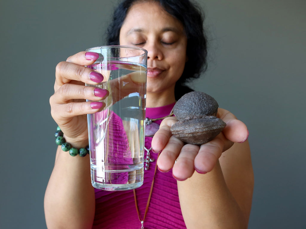 female holding glass of water and pair of moqui marbles