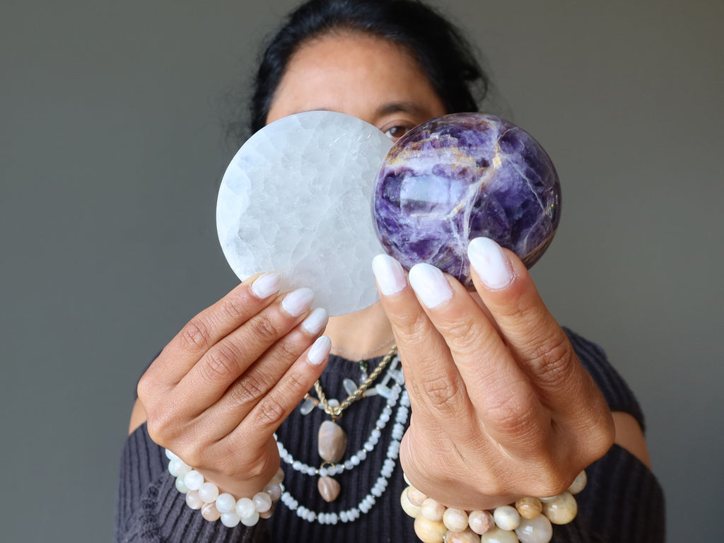 woman holding selenite circle and amethyst sphere