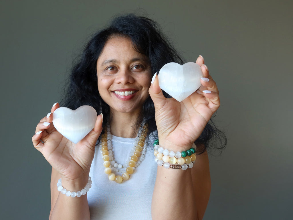 sheila of satin crystals holding two white selenite hearts