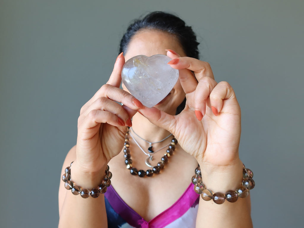 woman holding smoky quartz heart to her face wearing smoky quartz jewelry