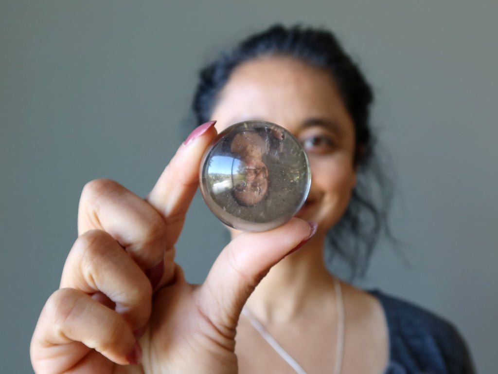 woman gazing in smoky quartz sphere
