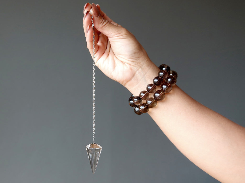 hand holding smoky quartz pendulum