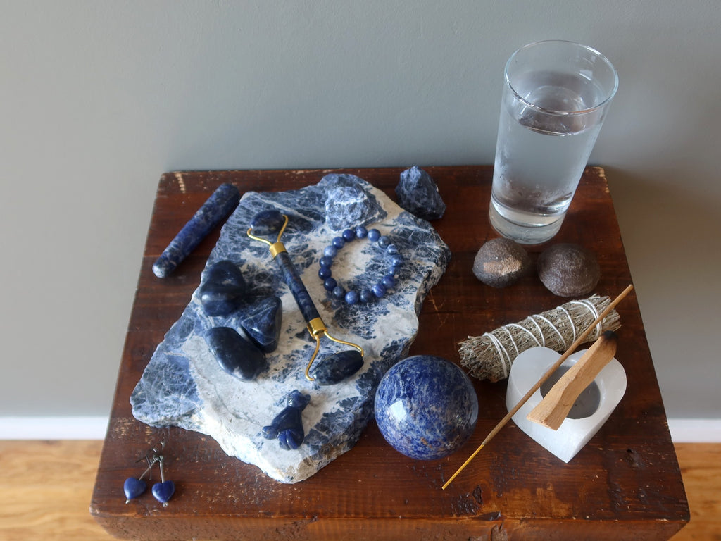 sodalite crystals and jewelry, incense, candle, sage, water, moqui balls